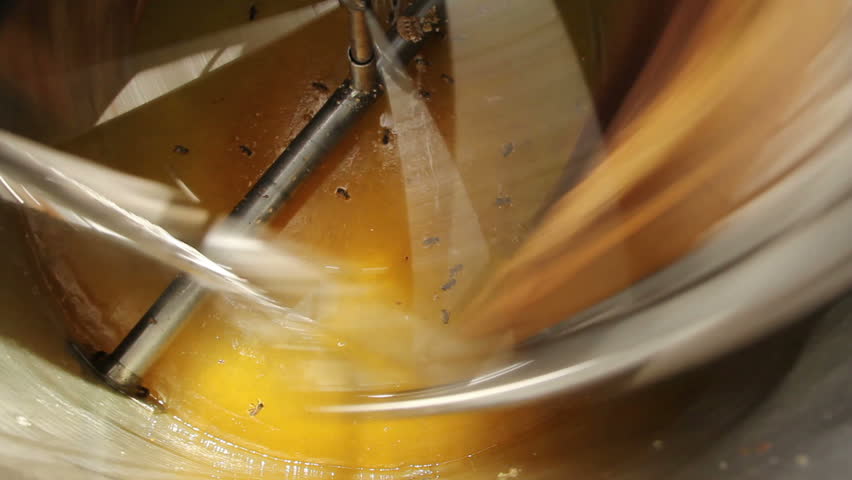 Honey being flung off a frame by centrifugal force inside an extractor during