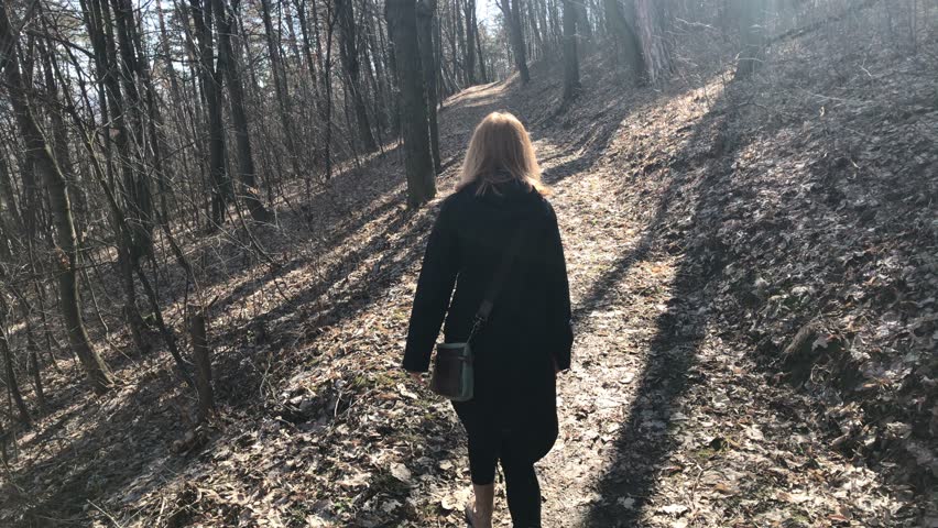 Woman on pathway leading through forest 
