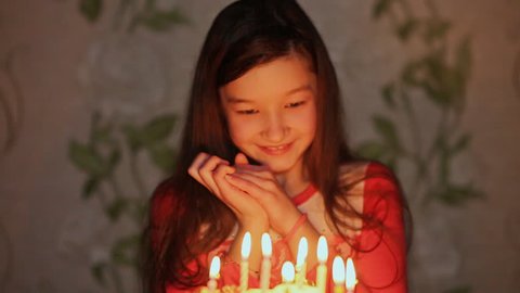 Girl closing her eyes make a wish and blows out the candles on the cake. Glad Day Birthday
