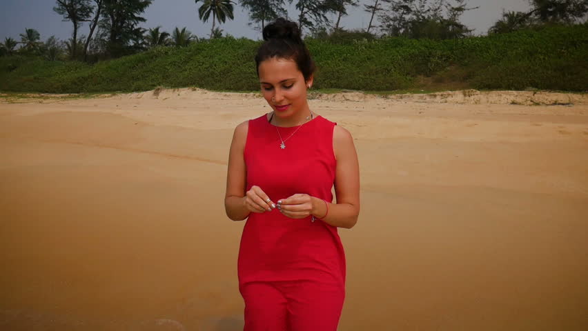 Beautiful woman in red dress walks at the sea side