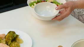Female hands poured the salad in portioned dishes.