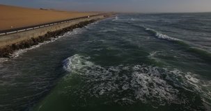 Drone video view of Namibian Atlantic coastline, road from Swakopmund to Walvis Bay along the coast, surf break point and landscape of ocean background and sand dunes at Namibia's west coast