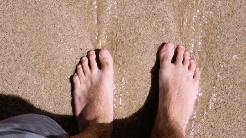Bare legs feet young man standing ocean shallows