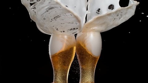 Having a toast with two glasses of beer and spilling. Shot with high speed camera, phantom flex 4K. Slow Motion.