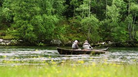 Dolly shot of senior men rowing boat while fishing on Nordic river