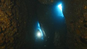 scuba divers exploring the caves tunnels caverns and swim thrughs underwater with torch and torch light