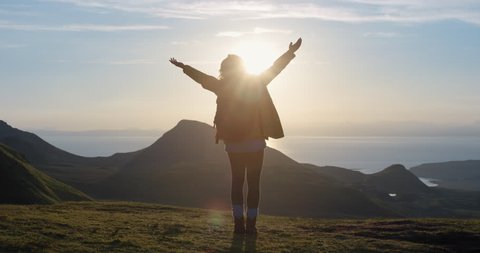 Woman with arms raised on top of mountain looking at Sunset view Hiker Girl lifting arm up celebrating life scenic nature landscape enjoying vacation travel adventure Isle of Skye Scotland