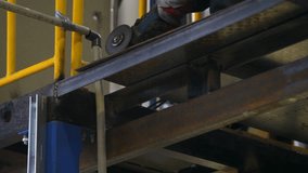 video shows metal construction installation process. This close-up shows metal cutting with small hand grinder with sparks flying down and metal is being cut. Video is taken indoors at factory site