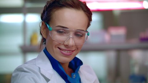 Happy researcher in lab. Lab researcher in safety glasses. Lab technician smiling. Female lab scientist smiling. Happy woman scientist face in laboratory. Female researcher portrait