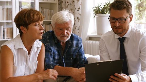 Front-view of Caucasian senior couple planning their investments with financial adviser at home