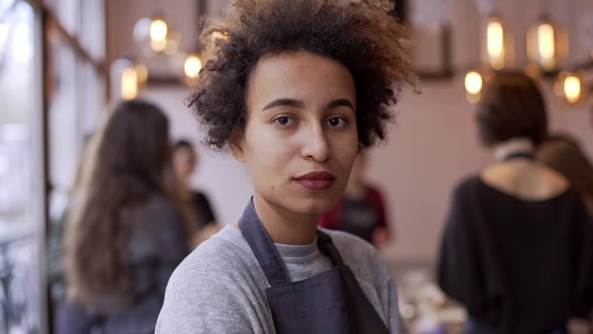 Close up footage of dark skinned female with afro haircut standing in crowded restaurant smiling in slowmotion Royalty-Free Stock Footage #24444425