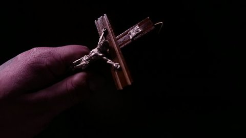 Hand in darkness with a crucifix closeup. 4K UHD