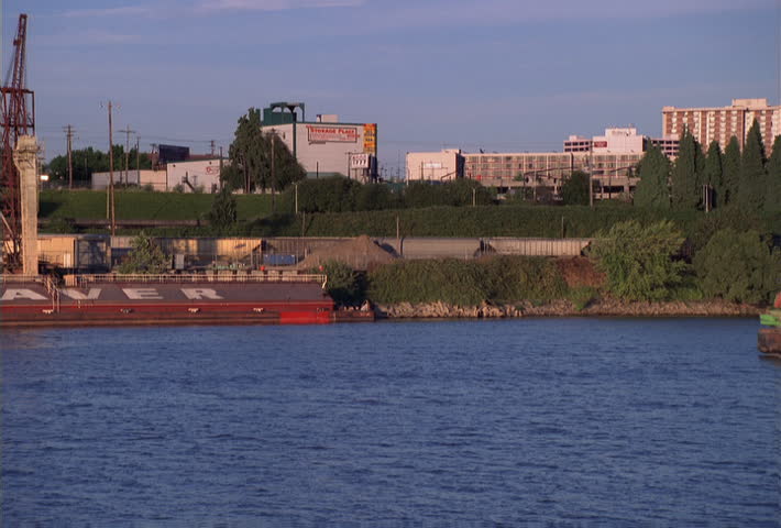 Loaded river barge cruising past industrial waterfront