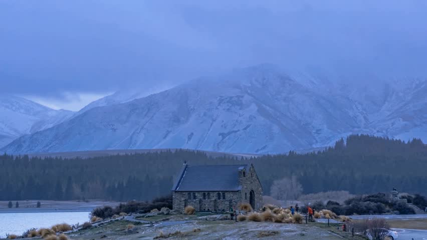 A heavy snow shower on Church of the Good Shepard in Tekapo, New Zealand with movement of tourists