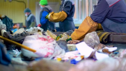 Workers at conveyor sorting garbage at a recycling plant.