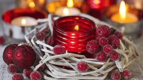 A tealight in a red glass holder and Christmas decorations