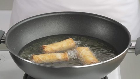 Removing deep-fried spring rolls from the pan