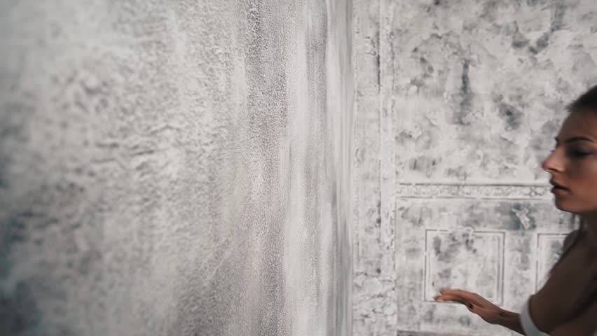 Beautiful long-haired blond woman in a white underwear on the background of a concrete wall