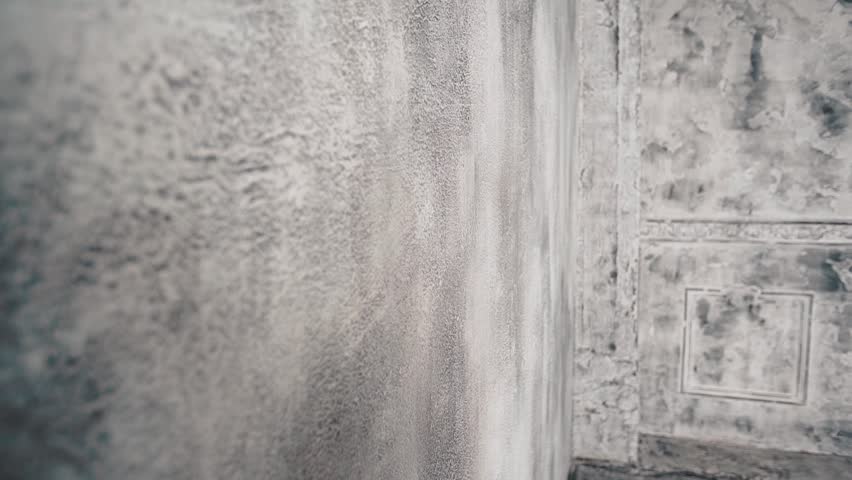 Beautiful long-haired blond woman in a white underwear on the background of a concrete wall