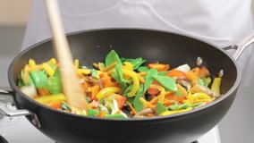 Mixing broccoli with other vegetables in a wok