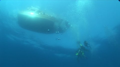 scuba divers ascending underwater from the boat underwater surface background with air bubbles 