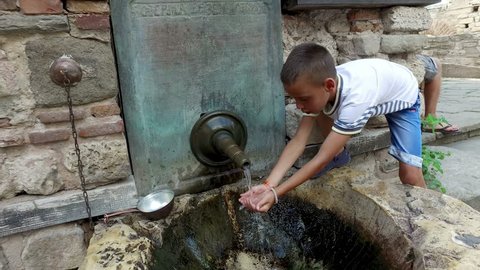 boy drinking water and washing hands from ancient oriental tap in the old city of Nesebar, Bulgaria