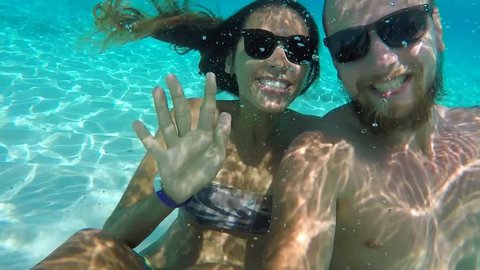 Young Happy Couple in Sunglasses Making Funny Underwater Selfie with GoPro Camera. HD Slow Motion. Thailand.