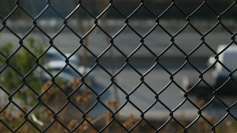 Chain link fence in sharp focus with traffic moving in the background. Don Valley Parkway, Toronto, Ontario, Canada.
