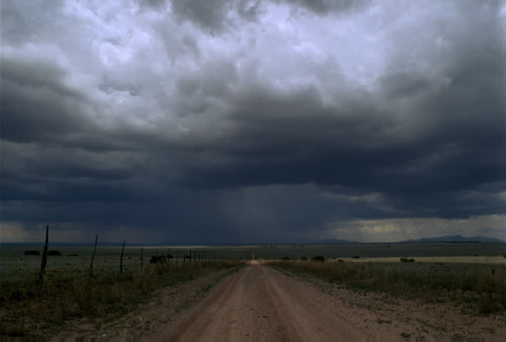 Time-lapse advancing storm clouds passing over a prairie road