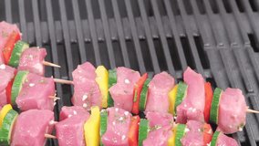 Meat and vegetable kebabs being placed on a grill