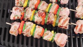 Meat and vegetable kebabs on a grill being brushed with oil marinade