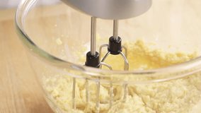 Biscuit dough being mixed with a hand mixer and eggs being added