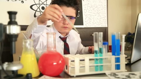 Cute schoolboy making science experiments with lab equipment at school