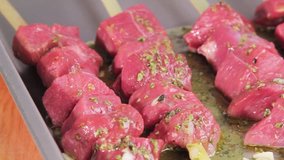 Lamb kebabs being drizzled with a herb marinade