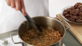 Onion and garlic being fried and pieces of meat being stirred in