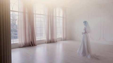 Beautiful Bride goes towards the large window in the bright room in slow motion