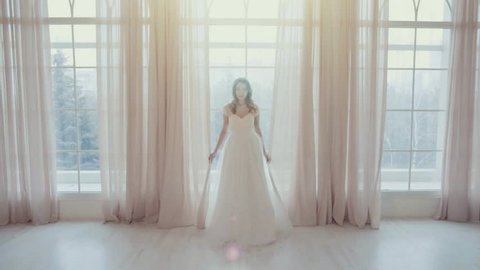 Beautiful bride stands in the middle of a large, bright room in slow motion