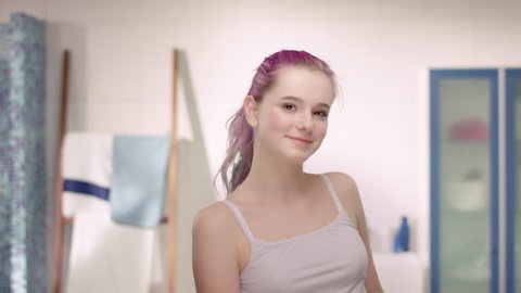 Young girl in puberty using antiperspirant in a modern bathroom