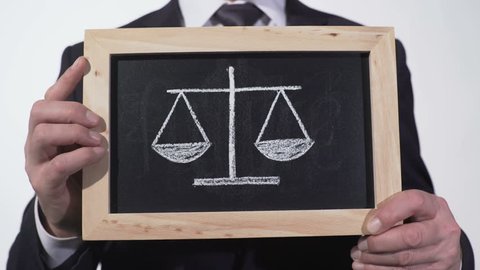 Justice scales drawn on blackboard in lawyer hands, decision pros and cons