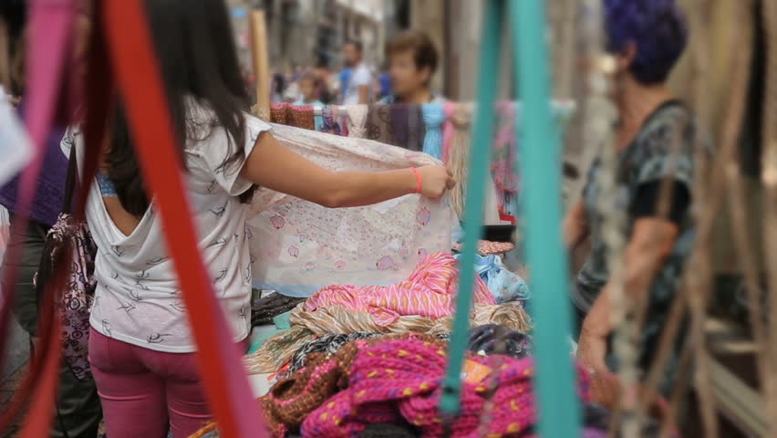 Colorful clothes for sale attracting buyers at market, women going shopping