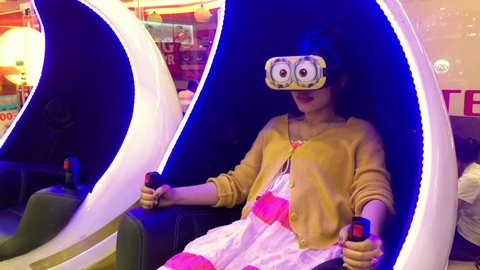VUNG TAU, VIETNAM - FEBRUARY 26, 2017: An unidentified girl wearing VR glasses sits in an armchair at the Lottemart shopping mall.