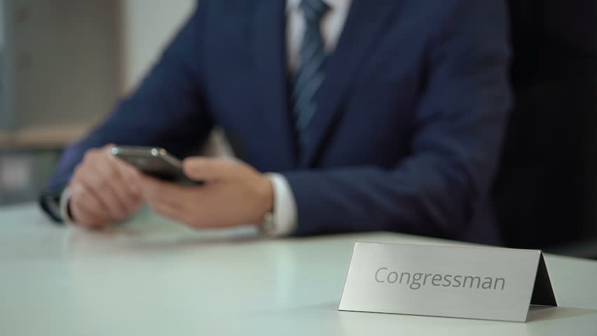 Congressman using smartphone for communication, examining political situation