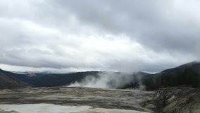 Pan timelapse of a smoking geysers and north entrance, filmed from the top of mammoth hot springs, in Yellowstone national park, in Wyoming, United states of america.: