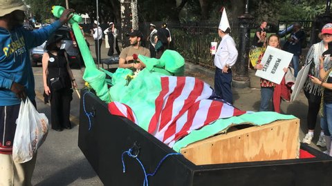 NEW ORLEANS, LOUISIANA CIRCA JANUARY 2017 - Activist interacts with fallen lady statue of liberty in coffin with american flag at anti Donald Trump inauguration day protest march performance art