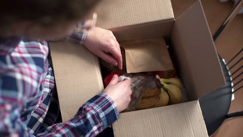 woman opening a Food delivery box at home. Food delivery services during coronavirus pandemic for working from home and social distancing. Shopping online.