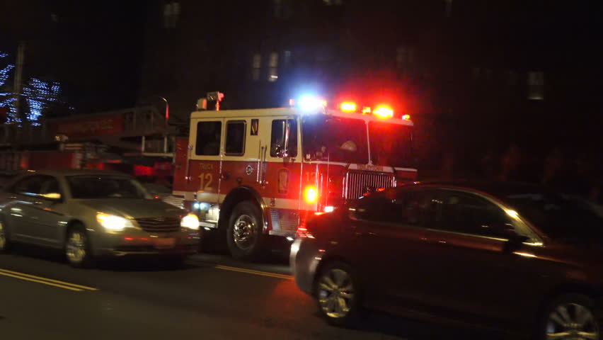 WASHINGTON, DC - FEB. 28, 2017: WASHINGTON, DC - FEB. 28, 2017: Aerial fire truck passes, siren, at night fire scene. As engine passes, see 2nd aerial truck w ladder raised at apartment building.