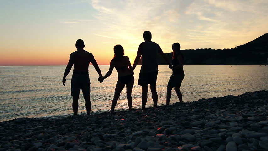 Group of people dancing on the beach at sunset, group of happy young people