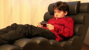 School child lying on a couch using mobil phone in home. Smartphone addiction