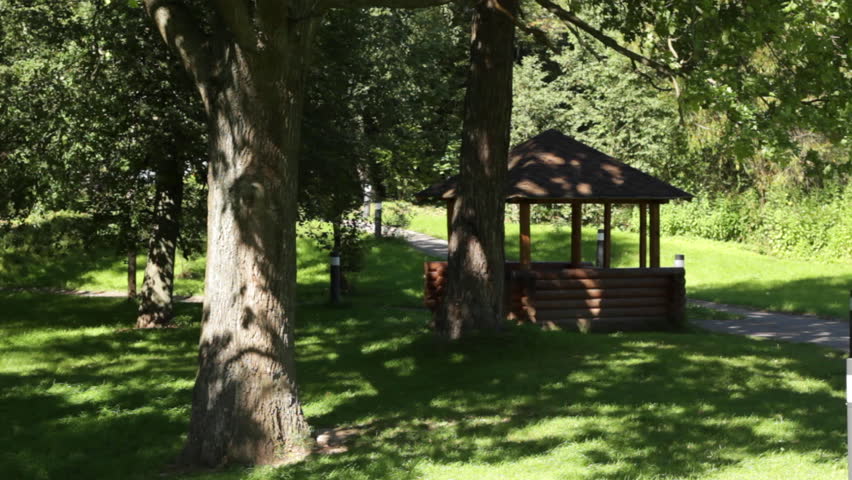Wooden summer house (pavilion) in park amidst beautiful greenery