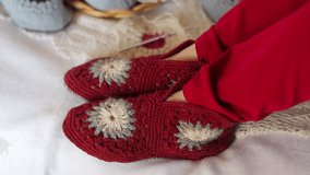 Female feet in knitted slippers are moving to the music. Close up